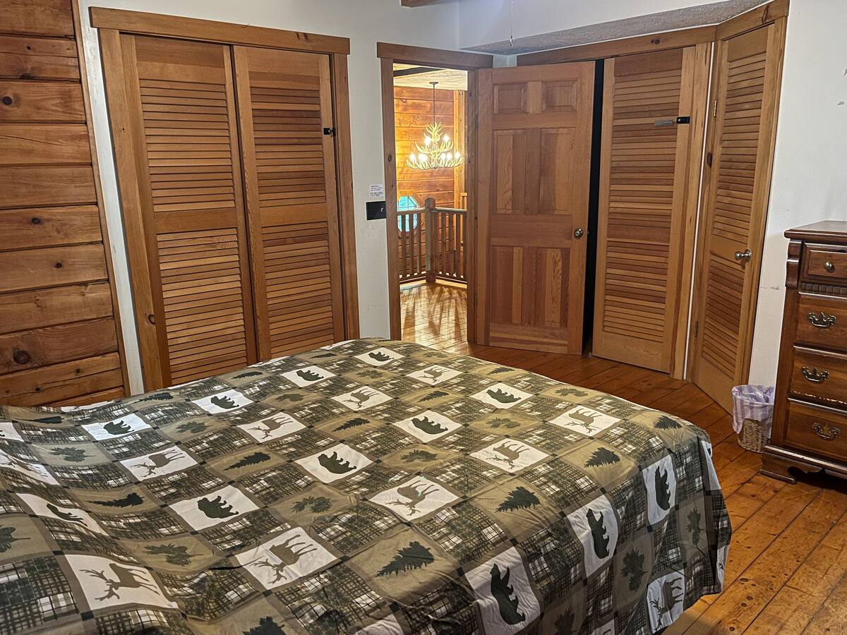 Wood-paneled bedroom with a woodland quilt