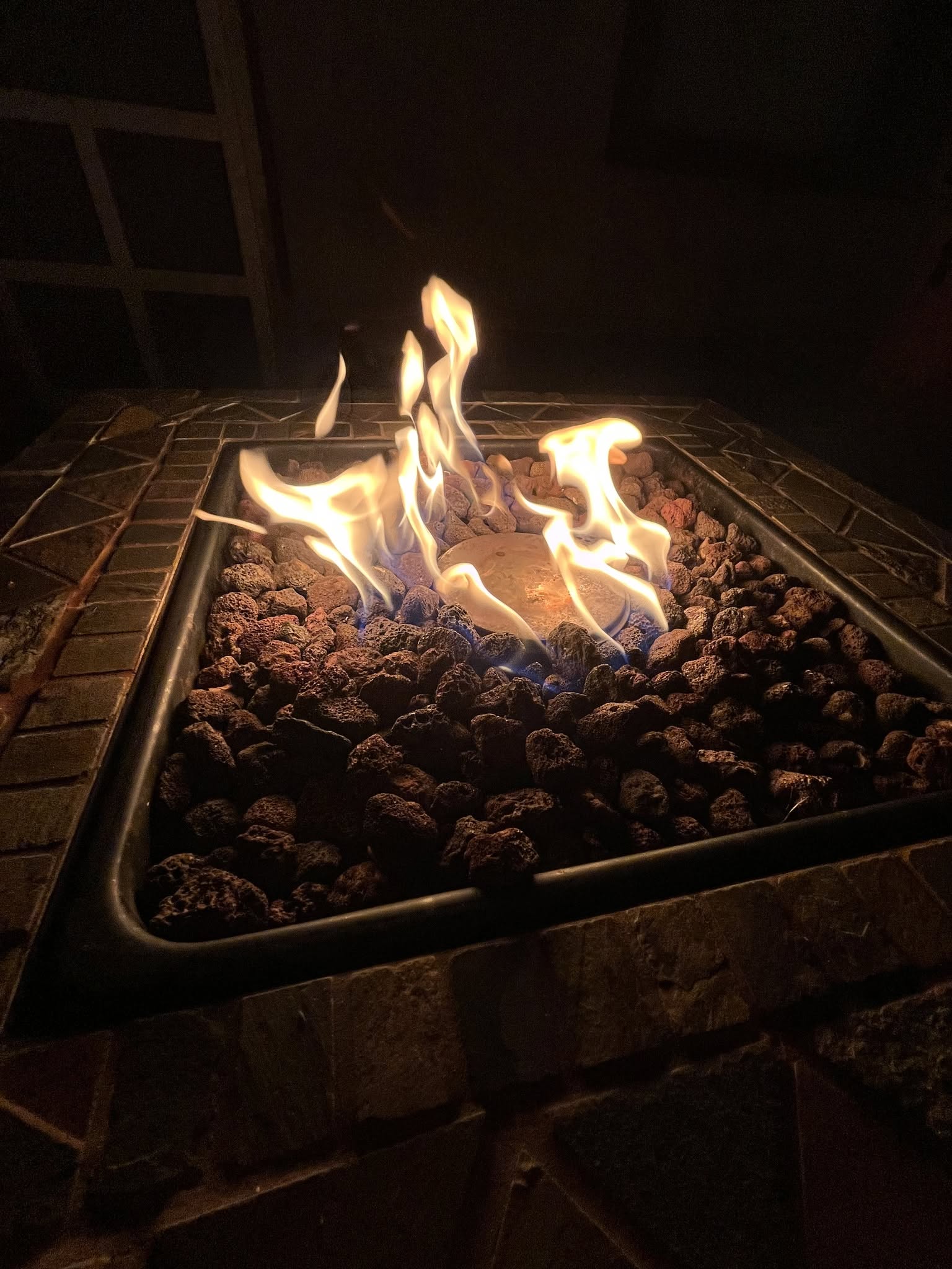 The handcrafted gas fire pit glowing after dark